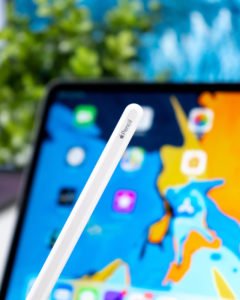 An Apple pencil with an iPad in the background